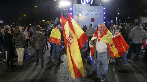 Algunos simpatizantes junto a la sede del Partido Popular, en la madrileña calle de Génova, siguiendo esta noche los primeros resultados electorales. EFE/Chema Moya