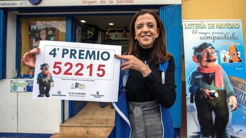 La propietaria de la administración número uno de las Torres de Cotillas (Murcia), muestra el cartel con el cuarto premio. EFE/Marcial Guillén