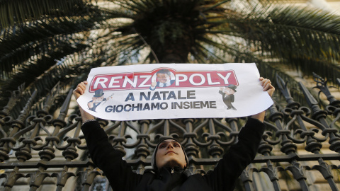 Un hombre sostiene una pancarta que dice "Renzipoly, jugamos juntos en Navidad" en frente del Banco de Italia, durante una protesta en Roma. REUTERS/Alessandro Bianchi