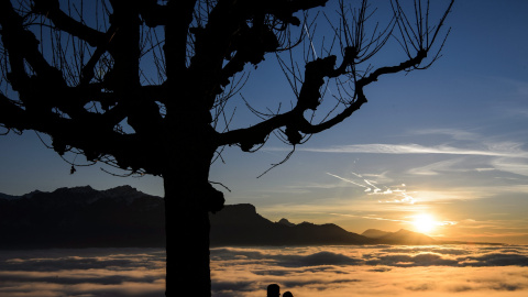 Una pareja contempla la puesta de sol en el lago de Ginebra cubierto de niebla en Chardonne, Suiza hoy 28 de diciembre de 2015. EFE/Jean-Christophe Bott
