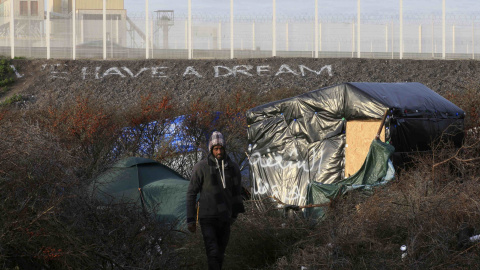 Un refugiado se pasea entre las tiendas en el campamento improvisado en Calais, donde se puede leer al fondo: "Tenemos un sueño",  30 de diciembre 2015 . REUTERS / Pascal Rossignol