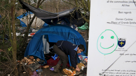 Un inmigrante limpia los alrededores embarrados de su tienda en el campamento provisional para refugiados de procedentes de Irak, Kurdistán, Irán y Siria, cerca de Dunkerque (Francia). REUTERS / Pascal Rossignol