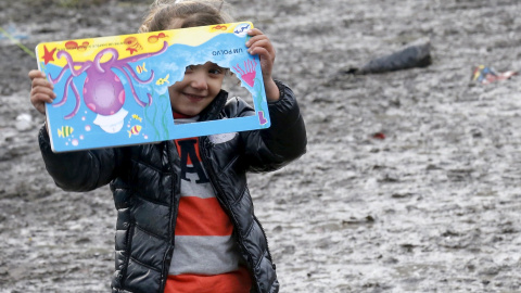 Una niña procedente del Kurdistán mira a través de una ventana de su libro infantil en un campamento provisional para refugiados de procedentes de Irak, Kurdistán, Irán y Siria, cerca de Dunkerque (Francia). REUTERS / Pascal Rossignol