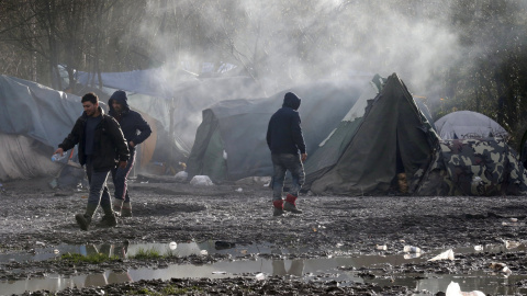 Los inmigrantes caminan por el suelo enfangado del campamento provisional para refugiados de procedentes de Irak, Kurdistán, Irán y Siria, cerca de Dunkerque (Francia). REUTERS / Pascal Rossignol
