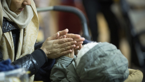 Una mujer calienta las manos de su hijo en una tienda de campaña a las puertas de la Oficina de Sanidad y Asuntos Sociales en Berlín. EFE/KAY NIETFELD