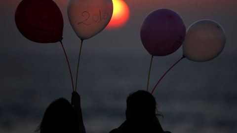 Dos jóvenes palestinas observan el atardecer mientras sostienen globos marcados con el año 2016 hoy, martes 29 de diciembre de 2015, en una playa de la Franja de Gaza. EFE/Mohammed Saber