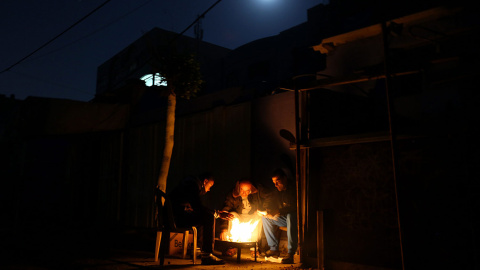 Refugiados palestinos se sientan alrededor de una hoguera durante un corte de luz en el campamento de refugiados de Al Shateaa, cerca de la playa, al oeste de la ciudad de Gaza el 27 de diciembre de 2015. EFE / EPA / MOHAMMED SABER