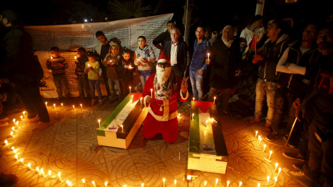 Un hombre vestido de Santa Claus, rodeado de velas, durante un acto para rendir homenaje a los palestinos asesinados recientemente por las tropas israelíes, el día de Navidad en Gaza.- REUTERS/Suhaib Salem