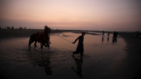 Un hombre camina con su caballo en Karachi, Pakistán