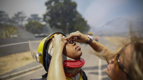 Una doctora echa solución salina en los ojos de un bombero en una calle de Ciudad del Cabo, Sudáfrica. EFE/NIC BOTHMA
