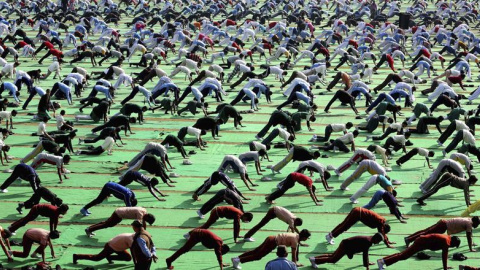 Profesores y estudiantes indios participan en una clase de yoga multitudinaria celebrada dentro del programa 'Surya Namaskar' con motivo del 153 aniversario del nacimiento de Swami Vivekanand en Bhopal, India. EFE/Sanjeev Gupta