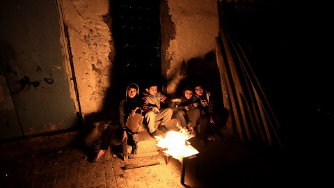 Un grupo de niños refugiados calentándose frente a una fogata luego de un corte de energía en medio del frío en el campamento Al Shateaa en Franja de Gaza. EFE/MOHAMMED SABER
