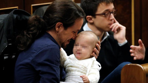 El líder de Podemos, Pablo Iglesias, con la hija de la diputada de su partido Carolina Bescansa en sus brazos en su escaño del Congreso.- EFE