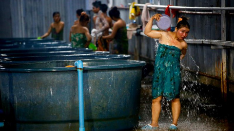 Trabajadoras migrantes se asean en unos baños comunitarios en el asentamiento de Samut Prakan, a las afueras de Bangkok (Tailandia). Cientos de obreros de la construcción habitan un singular asentamiento erigido a las afueras de Bangkok con
