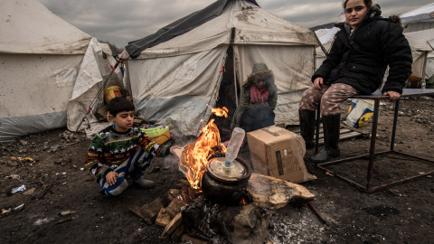 Varios inmigrantes intentan entrar en calor con un brasero en el campamento cerca de Dunkerque, donde viven alrededor de 2.500 de refugiados./AFP