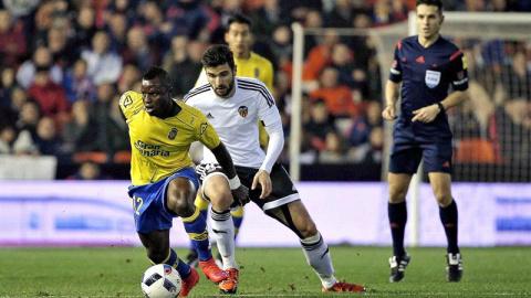 El centrocampista ghanés de Las Palmas Wakaso Mubarak (i) con el balón ante el defensa del Valencia CF, Antonio Barragán. /EFE