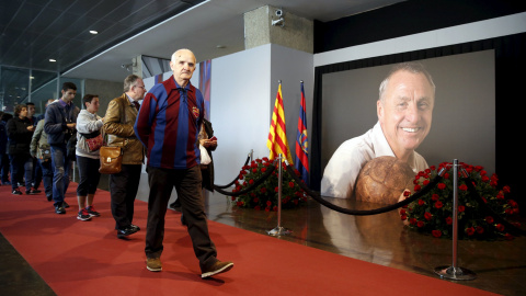 Los aficionados barcelonistas pasan por la foto de Johan Cruyff en el memorial instalado en el Camp Nou. REUTERS/Albert Gea