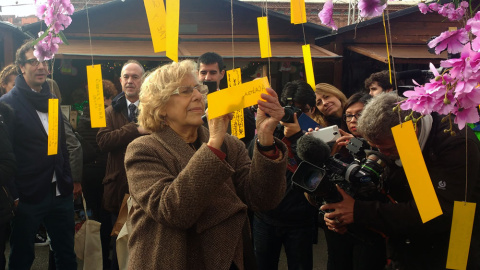 La alcaldesa de Madrid, Manuela Carmena, escribe "Que se acabe la guerra en Siria" en un árbol de los deseos./ J. Y. La alcaldesa de Madrid, Manuela Carmena, escribe "Que se acabe la guerra en Siria" en un árbol de los deseos./ J. Y.