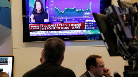 Los operadores de la bolsa de Wall Street observan un televisor en el patio de negociación, donde se informa de la subida de tipos en EEU. REUTERS/Lucas Jackson