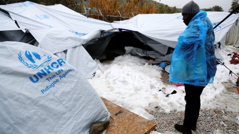 Un hombre trata de refugiarse del frío con un plástico en la isla griega de Lesbos. - REUTERS Un hombre trata de refugiarse del frío con un plástico en la isla griega de Lesbos. - REUTERS