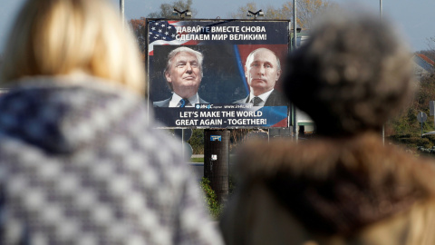 Un cartel que muestra fotos del presidente electo de Estados Unidos, Donald Trump, y del presidente ruso, Vladimir Putin, es visto a través de peatones en Danilovgrad. REUTERS