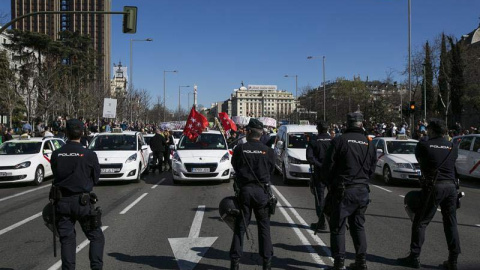 Agentes de la Policía Nacional vigilan durante la manifestación de los taxistas por el centro de Madrid. | SANTI DONAIRE (EFE) Agentes de la Policía Nacional vigilan durante la manifestación de los taxistas por el centro de Madrid. | SANTI DONAIRE (EFE)