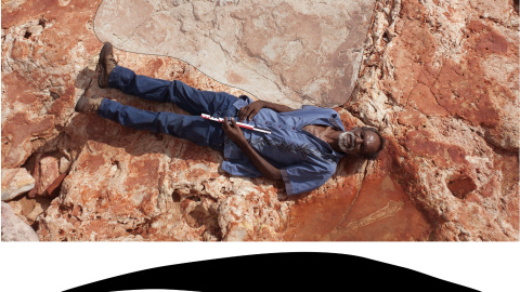 Richard Hunter, miembro aborigen del equipo investigador, yace junto a una huella de saurópodo./ UNIVERSITY OF QUEENSLAND