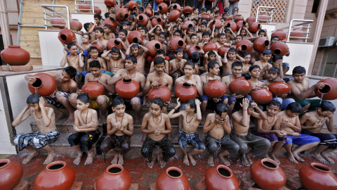 Estudiantes sostienen vasijas de barro llenas de agua mientras toman un baño sagrado antes del festival Magh Mela durante una ceremonia en Ahmedabad, India. REUTERS/Amit Dave