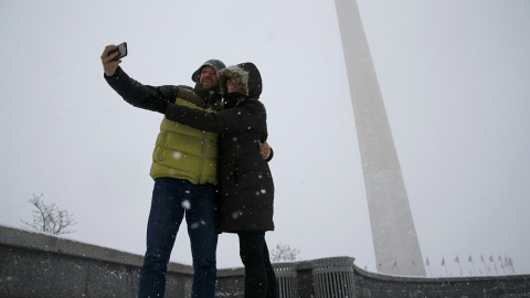 Dos personas se hacen un selfie frente al obelisco de Washington, bajo la nieve. /REUTERS