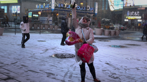 Unas turistas se hacen fotos bajo la nevada en Times Square (Nueva York). /REUTERS