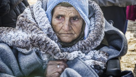 Una anciana en silla de ruedas llega junto con otros emigrantes y refugiados a la aldea de Miratovac después de cruzar a Serbia por la frontera con Macedonia, el 28 de enero de 2016./AFP/ARMEND NIMANI