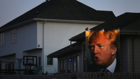 Un partidario de Donald Trump coloca un póster gigante del político iluminado con focos en la parte trasera de su casa para mostrar su apoyo al candidato./AFP/Christopher Furlong