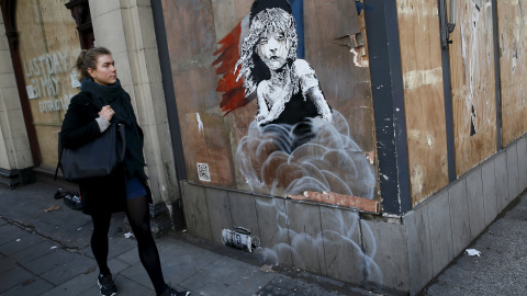 Una mujer pasa junto al nuevo graffiti de Banksy, frente a la embajada francesa en Londres. REUTERS/Stefan Wermuth