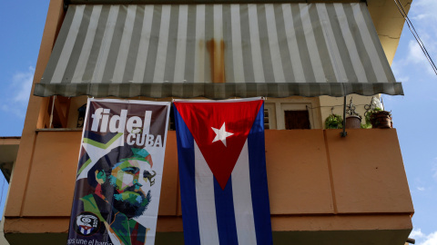 Una bandera con la cara de Fidel Castro colgando del balcón de una casa, al lado de una bandera de Cuba en la Habana. / REUTERS