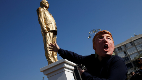 Una persona con una máscara de Donald Trump, junto a la estatua del primer ministro de Israel Benjamin Netanyahu, antes de ser derruida. REUTERS/Baz Ratne