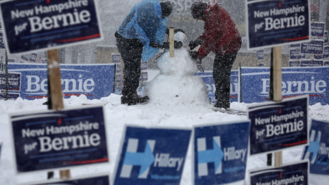 Trabajadores construyen un muñeco de nieve rodeado de carteles electorales. REUTERS/Carlo Allegri