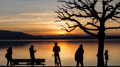 Un grupo de personas observa una puesta de sol en el lago Zug, Suiza. EFE/Alexandra Wey