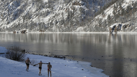 Los miembros de un club de natación calientan en la orilla del río Yenisei antes de su sesión semanal de baño en Divnogorsk, Rusia. REUTERS/Ilya Naymushin