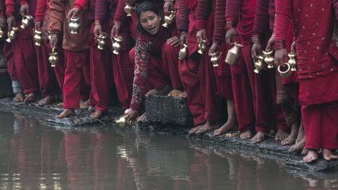 Una mujer hindú toma agua sagrada del río Bagmati frente al templo Pashupati durante la celebración del festival Madhav Narayan, en Katmandú (Nepal). EFE/Narendra Shrestha