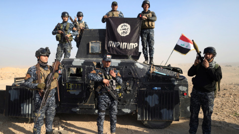 Miembros de la policía federal posan con la bandera del Estado islámico a lo largo de una calle de Albu Saif, al sur de Mosul, Irak. REUTERS/Zohra Bensemra