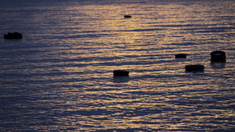 Varios neumáticos, utilizados como salvavidas por refugiados y migrantes, flotan en el mar cerca de la costa de Mytilini, en la isla de Lesbos, Grecia. EFE/Orestis Panagiotou