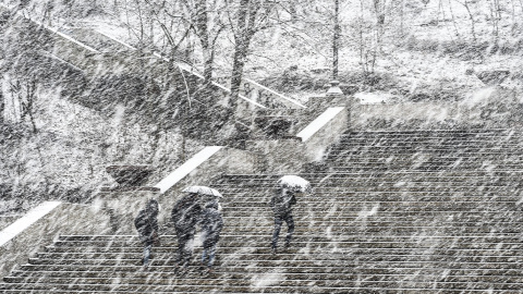 Varios viandantes suben por una esclinata bajo una fuerte nevada en el centro de Praga, República Checa. EFE/Filip Singer