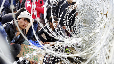 Refugiados permanecen junto al alambre de púas colocado en la frontera entre Grecia y Macedonia, cerca de Gevgelija. EFE/Nake Batev