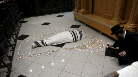 Un judío ultra-ortodoxo coloca una vela al lado del cuerpo del rabino Yochanan Sofer, el líder espiritual de la dinastía Erlau, durante su entierro en Jerusalén. REUTERS/Ronen Zvulun