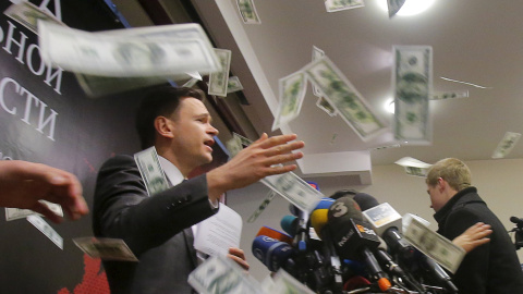 Una persona lanza trozos de papel, que simulan ser billetes, mientras el representante de la oposición rusa Ilya Yashin presenta uninforme sobre la situación actual de Chechenia, en Moscú. REUTERS/Maxim Shemetov