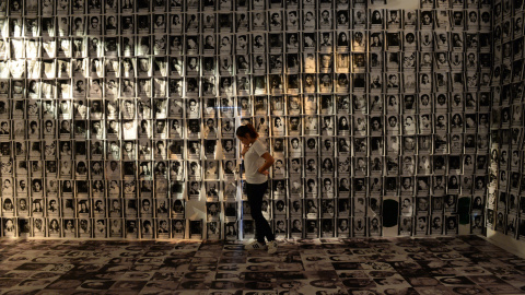 Una mujer se encuentra entre las fotos tomadas de víctimas de derechos humanos que se muestra en un museo en un campo militar en Manila el 24 de febrero de 2016. Filipinas celebra esta semana sus 30 años de democracia. AFP / TED ALJIBE