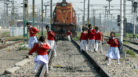 Estudiantes indios cruzan las vías del tren para ir a casa después de clase en la estación de trenes de la ciudad de Jalandhar./ AFP/ Shammi MEHRA