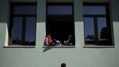 Los niños se sientan en una ventana de un edificio utilizado como dormitorio en un campo de refugiados e inmigrantes en Schisto, cerca de Atenas, Grecia, 25 de febrero de 2016. REUTERS / Alkis Konstantinidis