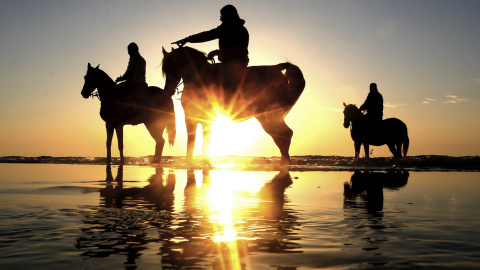 Jóvenes palestinos montando a caballo en la playa al oeste de la Ciudad de Gaza. EFE/MOHAMMED SABER