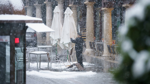 Un hombre recoge la terraza de un bar de Teruel bajo una intensa nevada.EFE/Antonio García